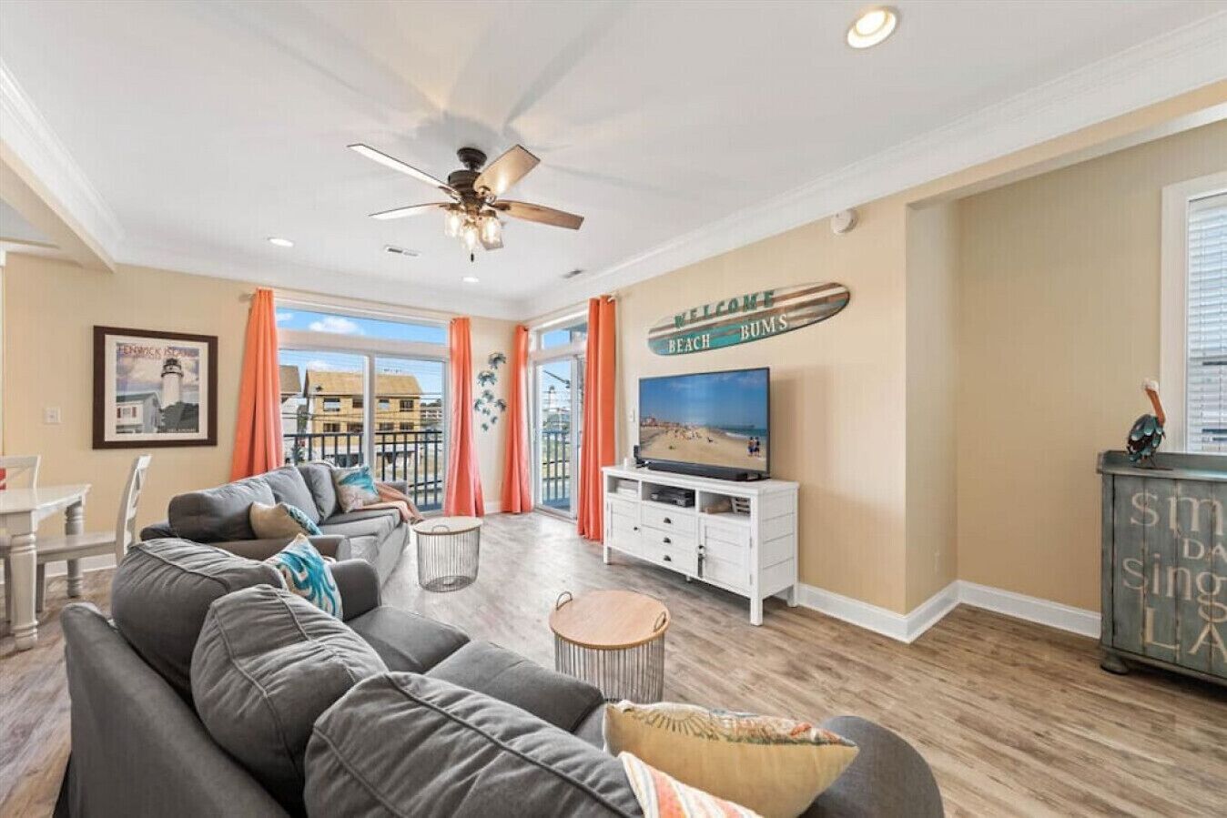 A spacious living room with a grey sofa, a TV, and a ceiling fan.