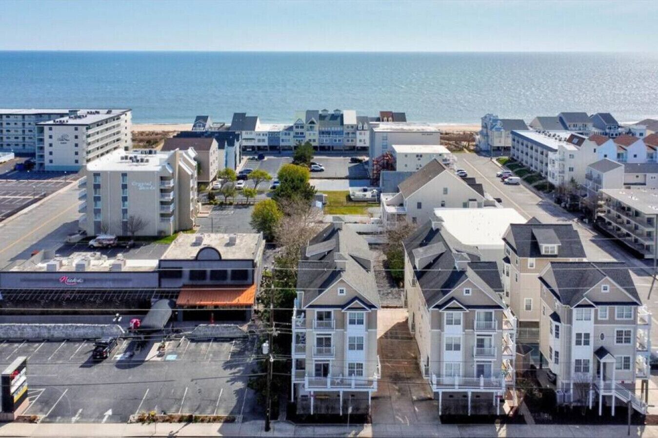 Un quartier résidentiel situé sur la côte, avec des immeubles à plusieurs étages, un parking et une vue sur l’océan.