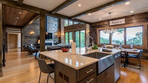 Una cocina amplia con una isla grande, vigas de madera y ventanas grandes que ofrecen vistas al exterior.