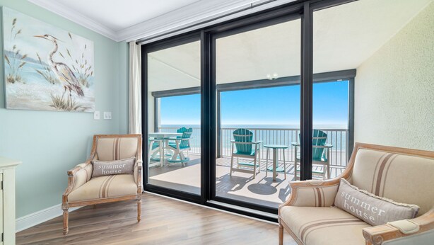 Une pièce dotée d’une grande porte-fenêtre coulissante donnant sur un balcon aménagé avec du mobilier d’extérieur.