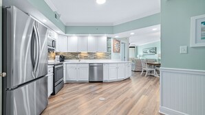 Une cuisine moderne avec des armoires blanches, des appareils en acier inoxydable et un plancher en bois.