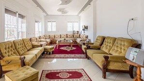 Ein geräumiges Wohnzimmer mit einer großen Sofagarnitur, einem Couchtisch und einem roten Teppich mit Muster.