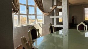 Ein Essbereich mit einem Glastisch, Stühlen und Blick durch große Fenster.