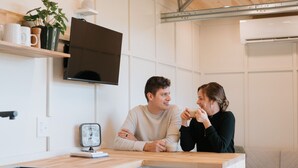 Une cuisine moderne avec un plafond en bois, des armoires blanches, un four encastré et une petite table à manger.