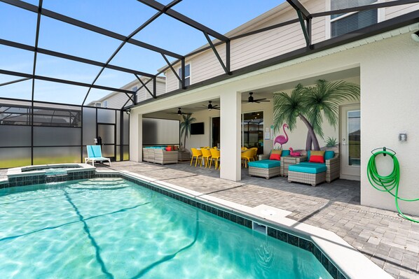 A swimming pool with clear water, surrounded by outdoor seating and a covered patio area.