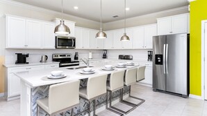 A modern kitchen with white cabinets, stainless steel appliances, and a central island with bar stools.