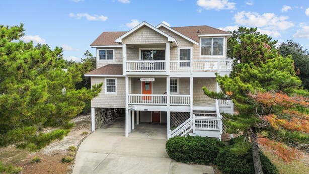 A two-story building with a red door, a balcony, and a sign that reads "Sands to Sea." - 1285 - Sands to Sea - Pet-Friendly Corolla Retreat Near the Beach (Corolla)