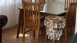 A dining area with wooden chairs and a glass table, a vase with branches, and a chandelier. - Creek Front House (Valley View)