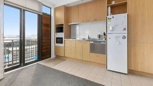 A modern kitchen with wooden cabinets, a white refrigerator, and a large window. - Roomy Loft with Free Parking by Zodiak Stays (Auckland)