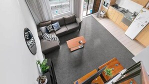 A modern apartment with a living area, kitchen, and balcony. - Roomy Loft with Free Parking by Zodiak Stays (Auckland)