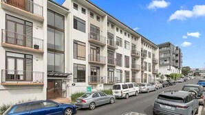 A multi-story residential building with balconies, a parking lot, and a clear sky. - Roomy Loft with Free Parking by Zodiak Stays (Auckland)