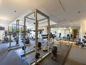 A gym with various exercise equipment, including a squat rack and free weights.