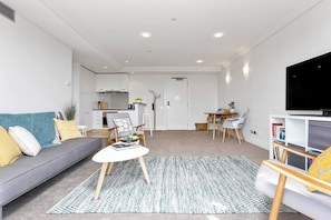 A modern living room with a sofa, coffee table, and TV stand.