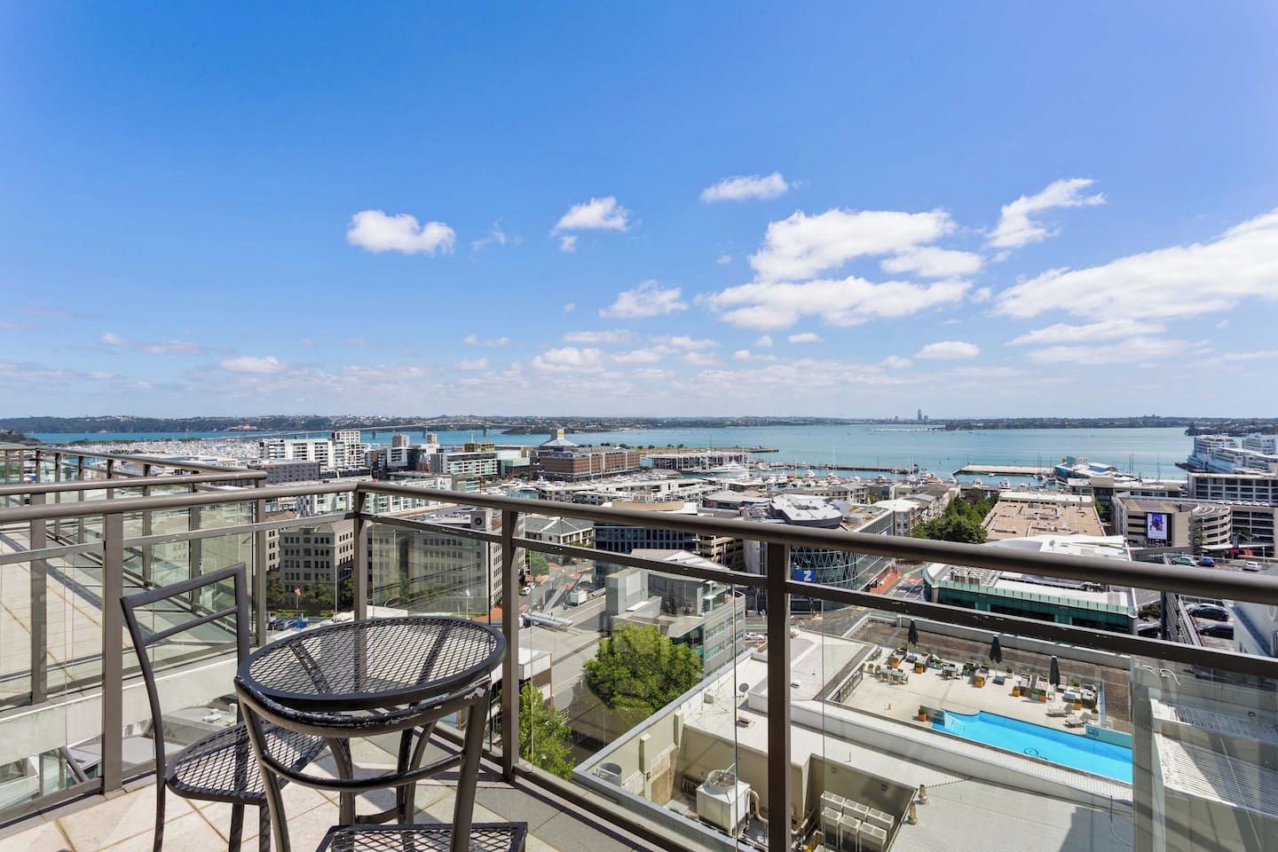 A balcony with a glass railing overlooking a cityscape and a body of water.