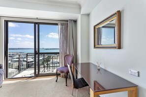 A hotel room with a balcony, a chair, a table, and a mirror.