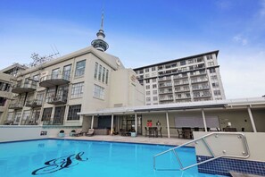 A hotel with a swimming pool, a tower, and a multi-story building with balconies.