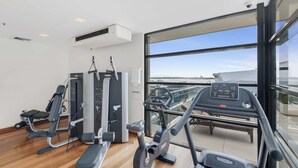 Un gimnasio con equipo de ejercicio, una cinta de correr y un amplio ventanal con vistas a la ciudad.