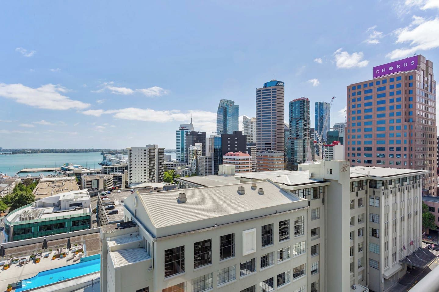 A city skyline with modern high-rise buildings, a waterfront, and a building with a sign that reads 'CHORUS'.
