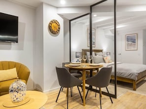 Une chambre moderne comprenant un lit, une table à manger avec des chaises, un téléviseur et un vase décoratif.