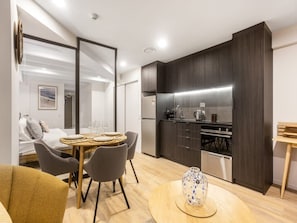 Une cuisine moderne avec des meubles de couleur sombre, un coin repas doté d’une table ronde et de chaises, et un réfrigérateur visible.