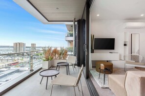 Ein Balkon mit Blick auf die Stadt, eine Couch, ein Fernseher und ein kleiner Tisch.