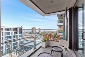 Un balcone con vista sulla città, un'area salotto e una pianta in vaso.