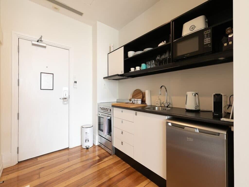 Una cocina compacta con muebles blancos, un microondas integrado y lavavajillas.
