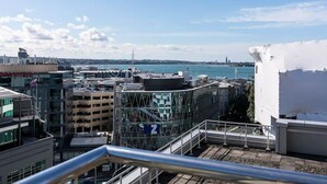 Paisatge urbà amb edificis moderns, cel serè i una vista llunyana d'una massa d'aigua.