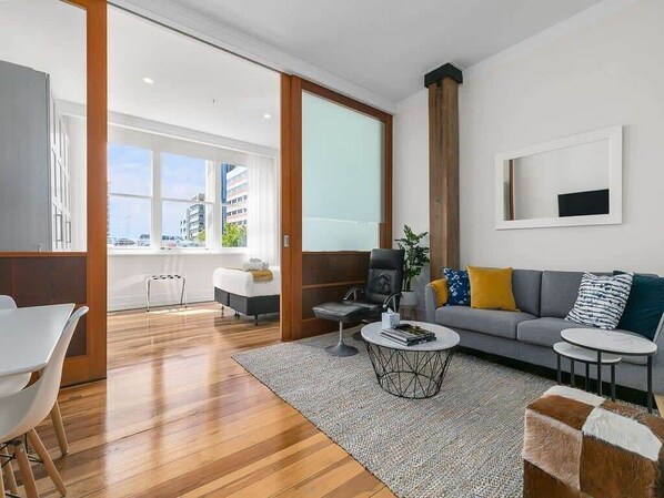 Un salon moderne avec un canapé, une table basse et un coin repas comprenant une table et des chaises blanches.