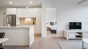 Un appartamento moderno con cucina, zona pranzo e camera da letto con televisore.