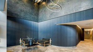 Una hall moderna con una parete curva, un tavolino rotondo, due divani e un lampadario dal design minimalista.