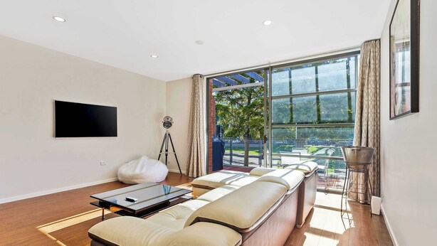 Een moderne woonkamer met een groot raam, een flatscreen televisie en een bank met kussens.