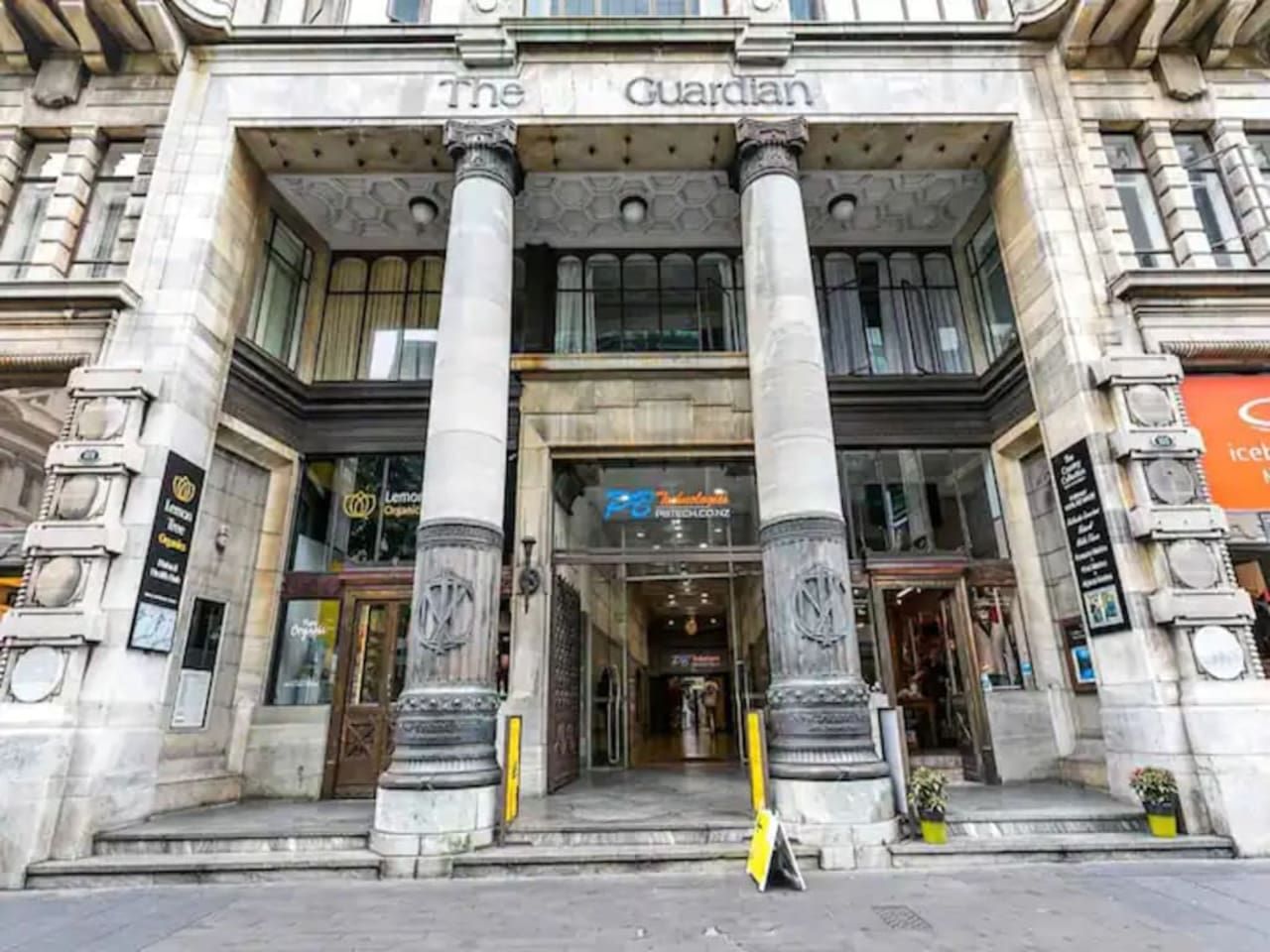 A building with a prominent entrance, columns, and a sign that reads 'The Guardian.'