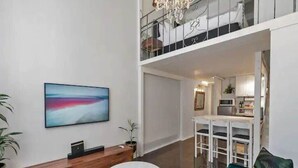 Een moderne woonkamer met een groot schilderij, een ronde salontafel, een bank en een keuken op de achtergrond.