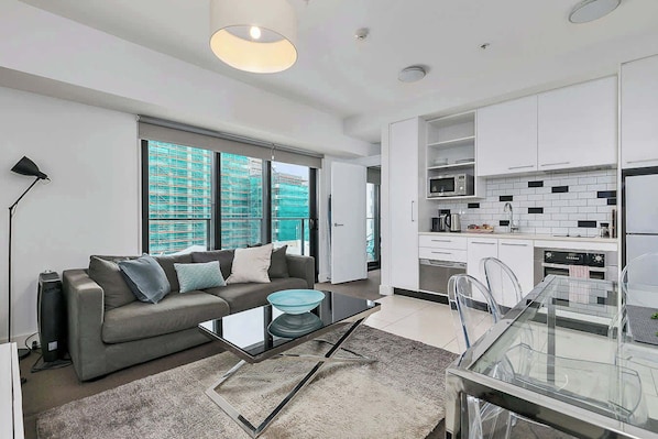 Un appartement moderne comprenant un canapé, une table basse, une table à manger et un coin cuisine.