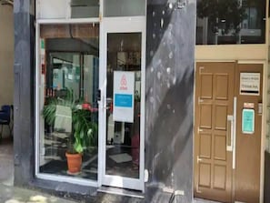 L’entrée d’un hôtel, avec une porte en verre, une enseigne indiquant « Airbnb » et une porte en bois portant l’inscription « Oceanic Hostel ».