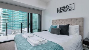 Ein modernes Hotelzimmer mit einem großen Bett, Blick auf eine Baustelle und einem Balkon mit Geländer.
