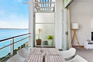 Un balcone con vista sul mare, un divano bianco, un tavolino e una lampada.