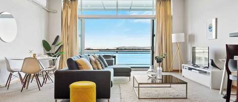 A modern living room with a sofa, coffee table, and dining area.