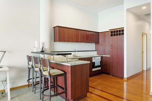 Une cuisine moderne avec des meubles en bois, un îlot central intégré doté de tabourets, une cuisinière et un évier.
