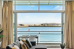 Una habitación con vista al frente marítimo, un sofá, una mesa y cortinas.