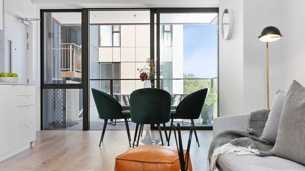 Een moderne woonkamer met een bank, een salontafel en een eethoek met stoelen en een tafel.