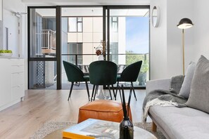 Een moderne woonkamer met een bank, een salontafel en een eethoek met stoelen en een tafel.