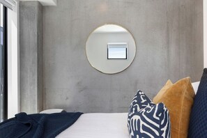 Un dormitorio con una cama, un espejo redondo y una ventana.