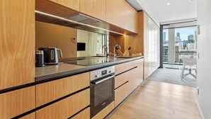 Eine moderne Küche mit Holzausstattung, einer Edelstahl-Dunstabzugshaube und Blick auf die Stadt durch große Fenster.