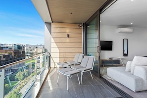 Un balcón con sofá, sillas y una mesa, con vistas a un paisaje urbano.
