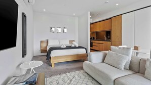 Ein modernes Schlafzimmer mit Bett, Sofa, einem kleinen Tisch und einem Fernseher.