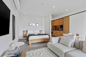 Une chambre moderne avec un lit, un canapé, une petite table et un téléviseur.