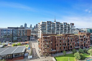 Un immeuble moderne à plusieurs étages, doté de balcons, d’un jardin sur le toit et offrant une vue sur le panorama urbain.