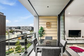 Ein moderner Balkon mit Essbereich, Fernseher und Blick auf die Stadt.